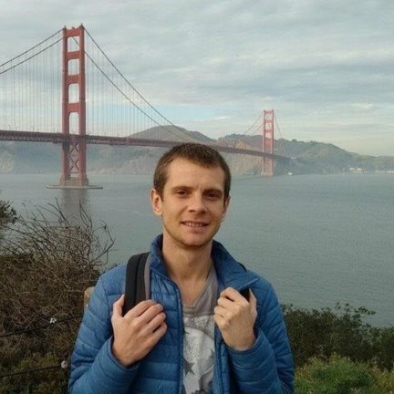 Denis smiling looking towards the camera in front of the Golden Gate Bridge in San Francisco