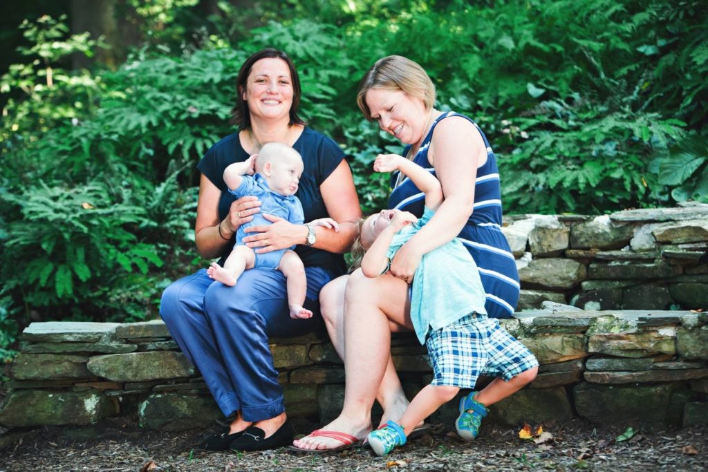 Allison and Stefania laughing with their two sons, sitting in a garden