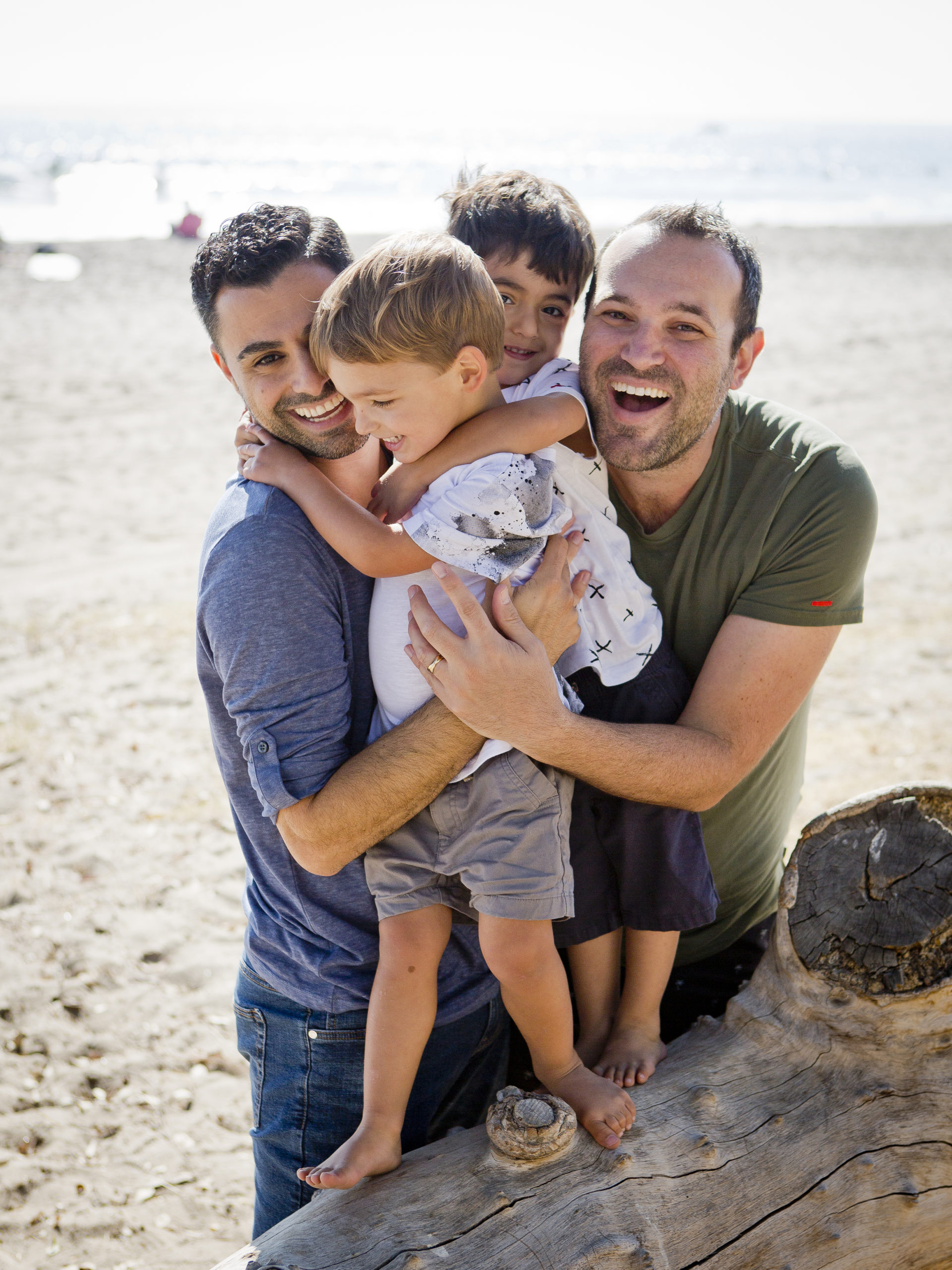Andrew and Elad holding their twin sons on a beach