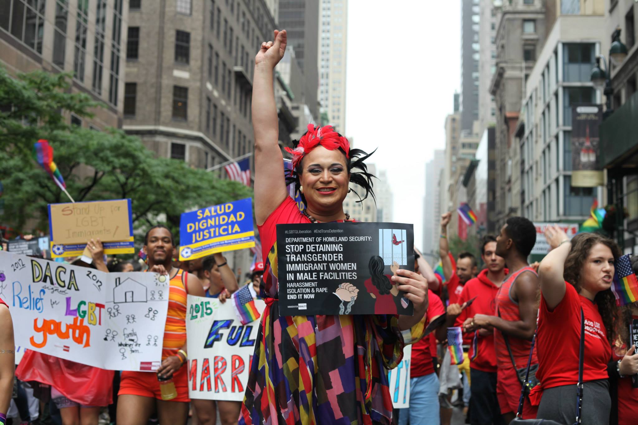 Ishalaa standing proudly with her fist in the air, in front of a protest advocating for LGBTQ rights
